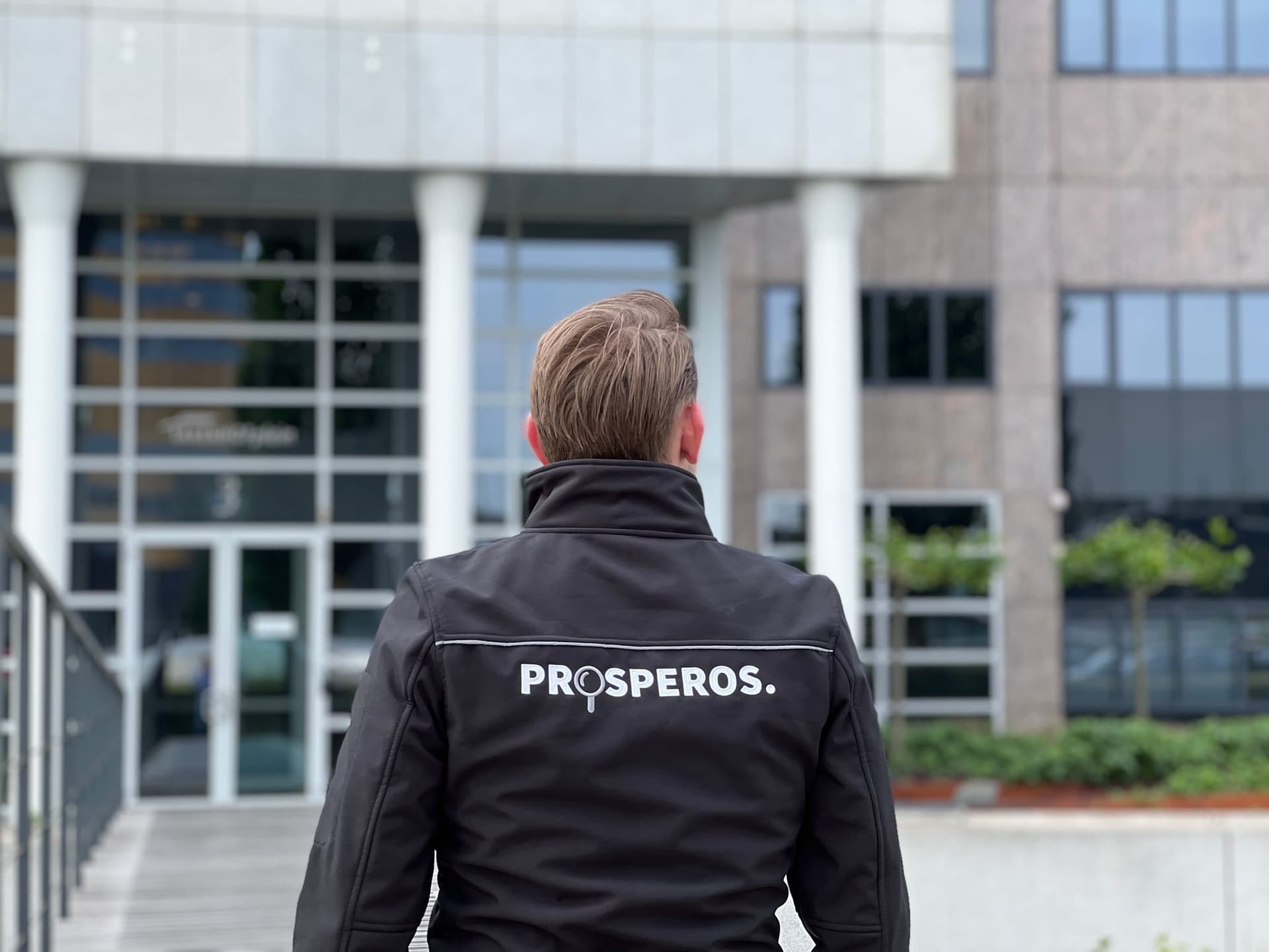 Inspecteur van Prosperos voor de ingang van een kantoorgebouw